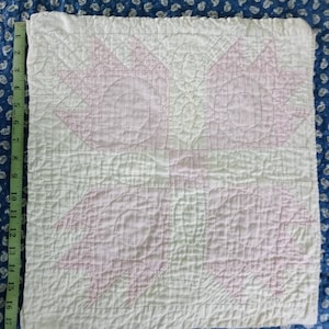 May include: A white and pink quilt with a star pattern. The quilt is quilted with a simple stitch pattern. The quilt is approximately 17 inches by 17 inches.