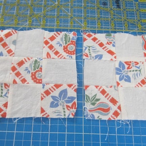 Op de afbeelding: Twee patchwork quiltblokken. Elk blok bestaat uit witte vierkanten en vierkanten met een bloemen- en geometrisch patroon in rood, blauw en groen. Op de achtergrond is een gele liniaal te zien.