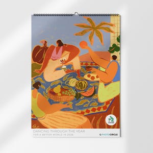 Könnte beinhalten: Ein Wandkalender mit Spiralbindung, der eine Illustration eines Picknicks zeigt. Die Kunst zeigt Figuren in Orange, Rosa und Gelb vor blauem Hintergrund, mit verschiedenen Früchten. Der Text unten lautet "DANCING THROUGH THE YEAR FOR A BETTER WORLD IN 2026."