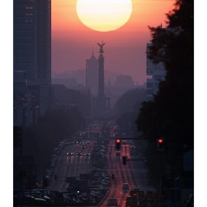 Peut inclure: Une page de calendrier pour juin pr&eacute;sentant une photographie d'une rue urbaine au coucher du soleil. Le soleil est un grand disque lumineux situ&eacute; derri&egrave;re la Colonne de la Victoire. La sc&egrave;ne inclut des b&acirc;timents, du trafic et un calendrier.