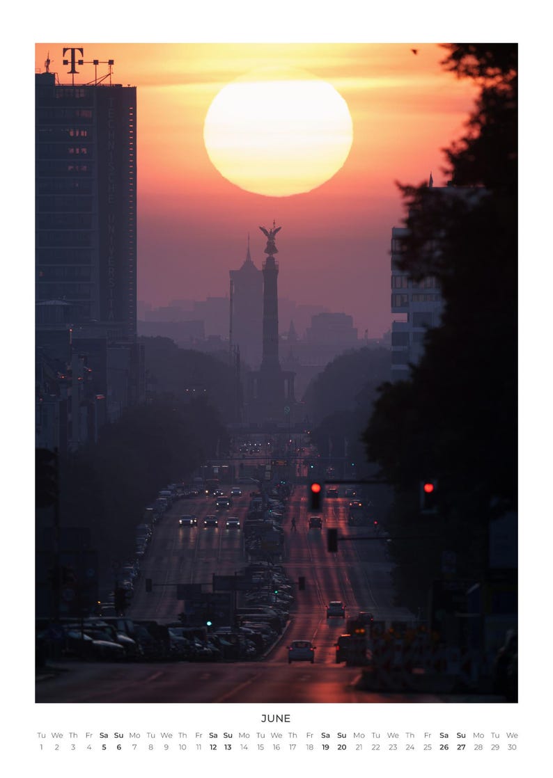 Peut inclure: Une page de calendrier pour juin pr&eacute;sentant une photographie d'une rue urbaine au coucher du soleil. Le soleil est un grand disque lumineux situ&eacute; derri&egrave;re la Colonne de la Victoire. La sc&egrave;ne inclut des b&acirc;timents, du trafic et un calendrier.