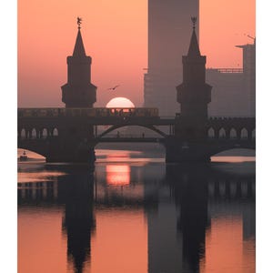 Peut inclure: Une page de calendrier pour septembre pr&eacute;sentant une photographie du pont Oberbaum &agrave; Berlin au lever du soleil. La silhouette du pont et d'un train se refl&egrave;tent dans l'eau sous un ciel orange vif. La grille du calendrier est imprim&eacute;e en bas.
