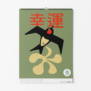 May include: A wall calendar with a sage green background featuring a black swallow with a red throat and a cream-colored belly. Above the bird are red Japanese characters. Below is a cream-colored abstract shape and a small circular logo.