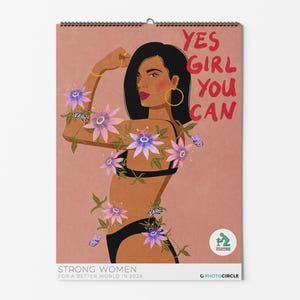 May include: A calendar with a woman flexing her arm, adorned with flowers and butterflies. The text "YES GIRL YOU CAN" is in red. The calendar is titled "STRONG WOMEN FOR A BETTER WORLD IN 2026".