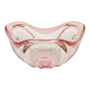 Peut inclure: Un bol en verre transparent doté d'un bord ondulé et festonné ainsi qu'une base arrondie. Le verre est rehaussé de touches de rose tendre sur les bords et la base, offrant un aspect translucide avec des contours lisses et incurvés.