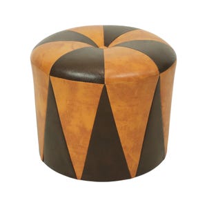 May include: Round ottoman with a geometric design. The top is divided into alternating brown and tan sections. The sides feature brown and tan triangular panels. The ottoman is made of leather and has a buttoned top.