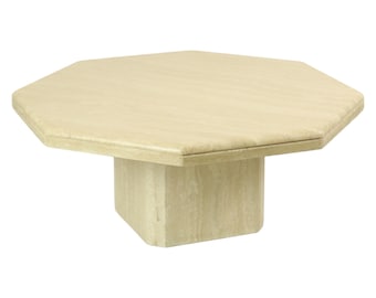 Könnte beinhalten: Achteckiger Travertin-Couchtisch mit quadratischem Sockel. Der Tisch ist hellbeige und hat eine glatte, polierte Oberfläche.