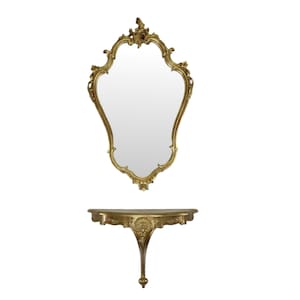 May include: A gold-toned ornate mirror with a scalloped frame and a matching console table with a curved top and ornate legs.