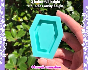 May include: A turquoise blue silicone mould shaped like a coffin with a 2 inch full height and 1.6 inch cavity height. The mould is held in a hand. The text "@kawaii.connection Etsy shop: KawaiiFindsCo" is at the bottom of the image.