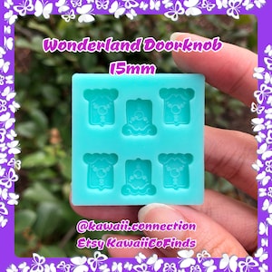 May include: A square, light blue silicone mold featuring six recessed cavities shaped like doorknobs, each measuring 15mm. The mold surface displays the text Wonderland Doorknob 15mm, @kawaii.connection, and Etsy KawaiiCoFinds in white lettering.
