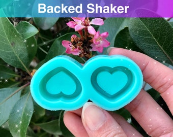 May include: A turquoise silicone mold with two 1 inch heart-shaped cavities. The mold is designed for making resin shaker charms.