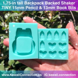 May include: A turquoise silicone mold for making resin crafts. The mold features a backpack design and separate molds for making tiny pencil and book shapes. The text "1.75-in tall Backpack Backed Shaker TINY 15mm Pencil & 13mm Book Bits" is printed on the mold.
