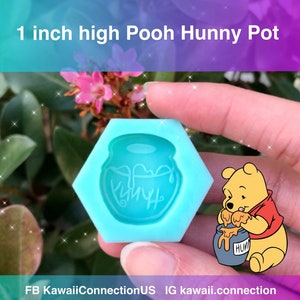 May include: A blue silicone mold shaped like a honey pot with the word "Hunny" written on it. The mold is 1 inch high.