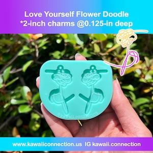 May include: A turquoise silicone mold for making two 2-inch flower charms. The mold is shaped like a flower with a stem and leaves. The mold is 0.125 inches deep. The text "Love Yourself Flower Doodle" and "@kawaii.connection" is printed on the mold.