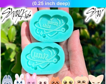 May include: Two turquoise silicone moulds for making resin crafts. Each mould is shaped like an oval and features a heart with a planet and stars around it. The text "Stray Kids" and "Stay" are written on the moulds. The moulds are 1.75 inches wide and 0.25 inches deep.