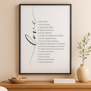 Pode incluir: Uma impressão emoldurada com uma borda preta apresenta a palavra "Love" em escrita cursiva. A impressão exibe uma lista de afirmações em uma fonte simples e elegante, incluindo "Love is kind" e "Love never fails."