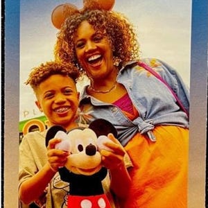 A Disney Springs multigraph guidemap brochure showing a smiling boy holding a Mickey Mouse plush toy next to a woman.