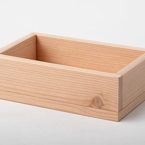A rectangular unfinished light wood box resting on a plain white surface.