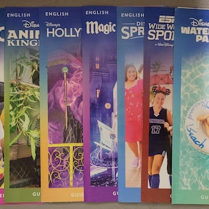 May include: A collection of Disney park guidebooks, including EPCOT, Animal Kingdom, Hollywood Studios, Magic, and Water Parks. Each guide features colorful graphics and images of attractions and characters. The guidebooks are vertically oriented.