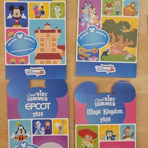 Four Cool Kids Summer 2026 guide maps for Hollywood Studios, Animal Kingdom, Epcot, and Magic Kingdom are arranged on a wooden surface.