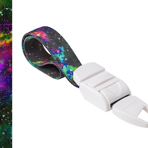 May include: A white tourniquet with a colourful galaxy print. The tourniquet is made of fabric and has a plastic buckle.