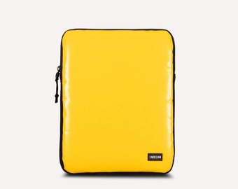 May include: Yellow laptop sleeve with a black zipper and the word "UNDEEUNI" printed on the front.