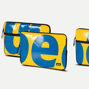 May include: Two yellow laptop sleeves with blue lettering. The sleeves have the word "IKEA" printed on them.