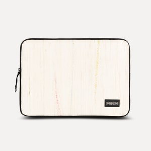 May include: White laptop sleeve with a colorful woven pattern and the word "UNBEGUN" in black text.