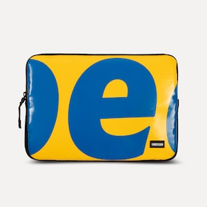 May include: Yellow laptop sleeve with a blue "e" and a blue circle on the front. The sleeve has a black zipper and the text "UNBEGEUN" in white.