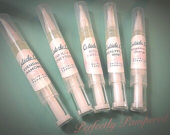 May include: Six clear bottles with white caps and labels. The labels have a floral design and text that reads "Cuticle Oil" and the scent of each oil. The scents are Lavender Chamomile, Vanilla Honey, Rose Sweet, Eucalyptus Mint, Bergamot Orange, and Perfectly Pampered.
