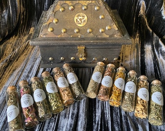 May include: A wooden box with a pentagram design on the lid, containing 12 small glass bottles filled with dried herbs. The bottles are labeled with the names of the herbs, such as "Rosemary" and "Calendula Flowers".