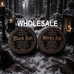 May include: Two round, black tins labeled "Black Salt" and "Witch's Ash" with gold lettering. The tins are surrounded by candles, a lantern, and a forest backdrop. The text "WHOLESALE" is displayed across the top.