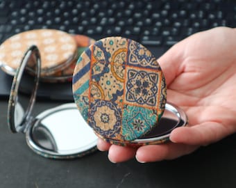 May include: A compact mirror with a colorful patterned cork design. The mirror is open and the reflective surface is visible.