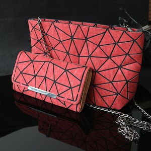 Pode incluir: Um conjunto de duas bolsas de mão de cortiça vermelha com um padrão geométrico. A bolsa maior tem uma alça de corrente e a bolsa menor é uma carteira.