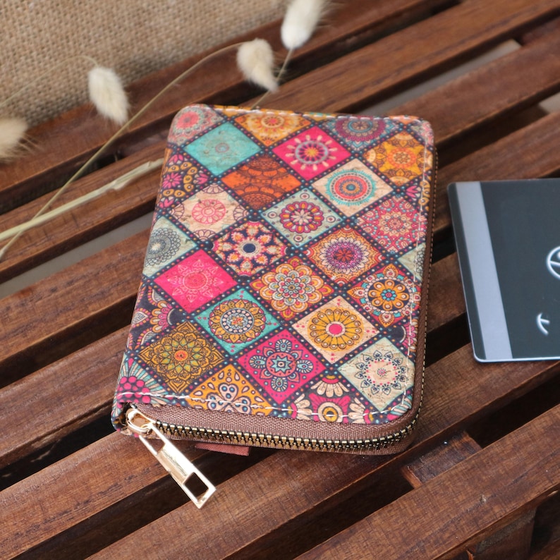 May include: A small, colourful zippered wallet with a geometric pattern of squares and circles. The wallet is made of a fabric material and has a gold zipper.