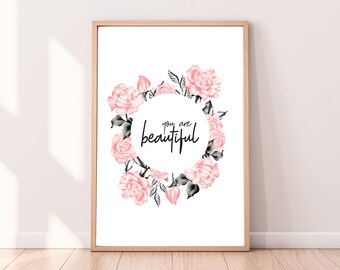 May include: A framed art print with a floral wreath of pink roses and green leaves surrounding the words "you are beautiful" in black script. The artwork is set against a white background.