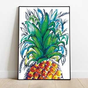 May include: A framed art print featuring a vibrant, hand-drawn pineapple illustration. The pineapple has a yellow and red body with a green crown and blue accents. The artwork is set against a white background.