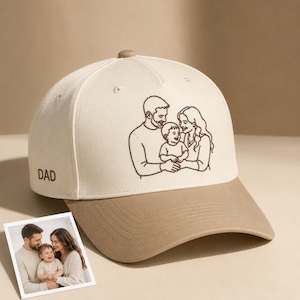 May include: A beige and tan baseball cap with an embroidered family portrait. The cap features a curved brim and the word "DAD" embroidered on the side. A small photo of the family is in the foreground.