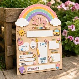 Puede incluir: Un letrero de madera para el primer día de clases con un arcoíris, nubes y el nombre Lily. Incluye secciones para edad, altura, favoritos y profesor, decorado con ilustraciones de un sol, autobús escolar, crayones, tijeras y lápiz.