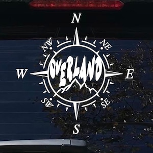 May include: White vinyl sticker of a compass with the word "OVERLAND" in the center. The compass points are labeled N, NE, E, SE, S, SW, W, and NW.