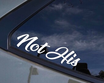 Può includere: Un adesivo in vinile bianco con il testo "Not His" in un font corsivo, applicato al lunotto posteriore di un'auto.