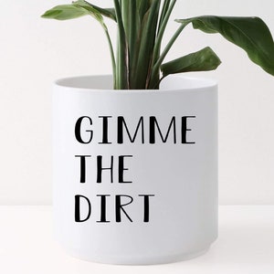 May include: White ceramic planter with black text that reads "Gimme the Dirt".