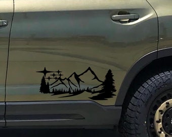 May include: A black vinyl decal of a mountain range with stars and trees, applied to the side of a green SUV.