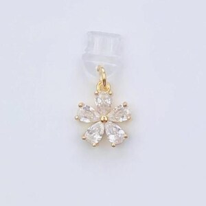 May include: A gold-coloured flower pendant with clear, teardrop-shaped stones. The pendant is attached to a clear earring backing and displayed on a white card with the text "Duchess Gems STUDIO".