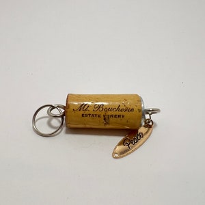 May include: A cork keychain with a silver ring and a gold charm that says "Peace". The cork is from Mt. Boucherie Estate Winery.