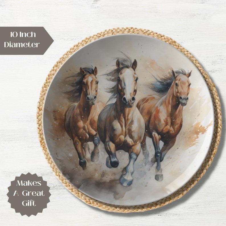 May include: A 10 inch diameter ceramic plate with a watercolor painting of three brown horses running. The horses are in a blurred motion, with their manes and tails flowing in the wind. The background is a light brown with splashes of white.