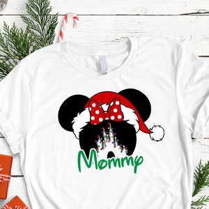 May include: White t-shirt with a black and white illustration of Mickey Mouse wearing a red Santa hat with a red bow. The text "Mommy" is written in green below the illustration.