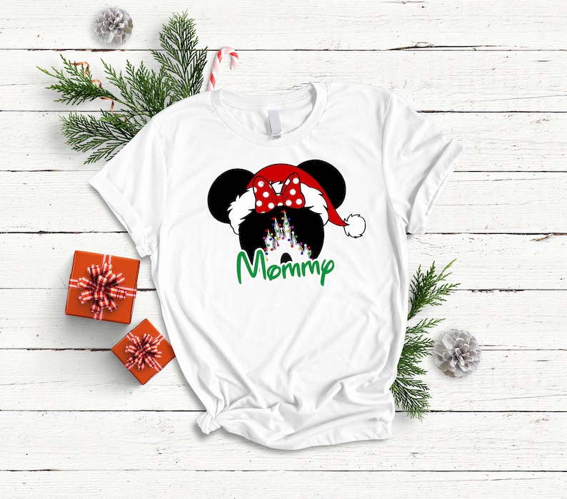 May include: White t-shirt with a black and white illustration of Mickey Mouse wearing a red Santa hat with a red bow. The text "Mommy" is written in green below the illustration.