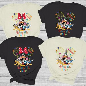 May include: Four t-shirts with a Disney theme. Each shirt features a Mickey Mouse head design with the text "Disney Trip 2026" and the option to add a name. The shirts are in black, cream, and beige.