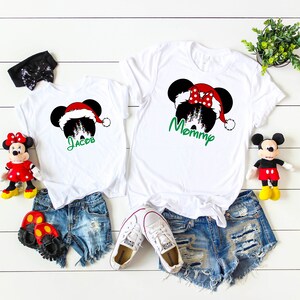 May include: White t-shirts with a Christmas Mickey Mouse design. The adult shirt says "Mommy" and the child's shirt says "Jacob".